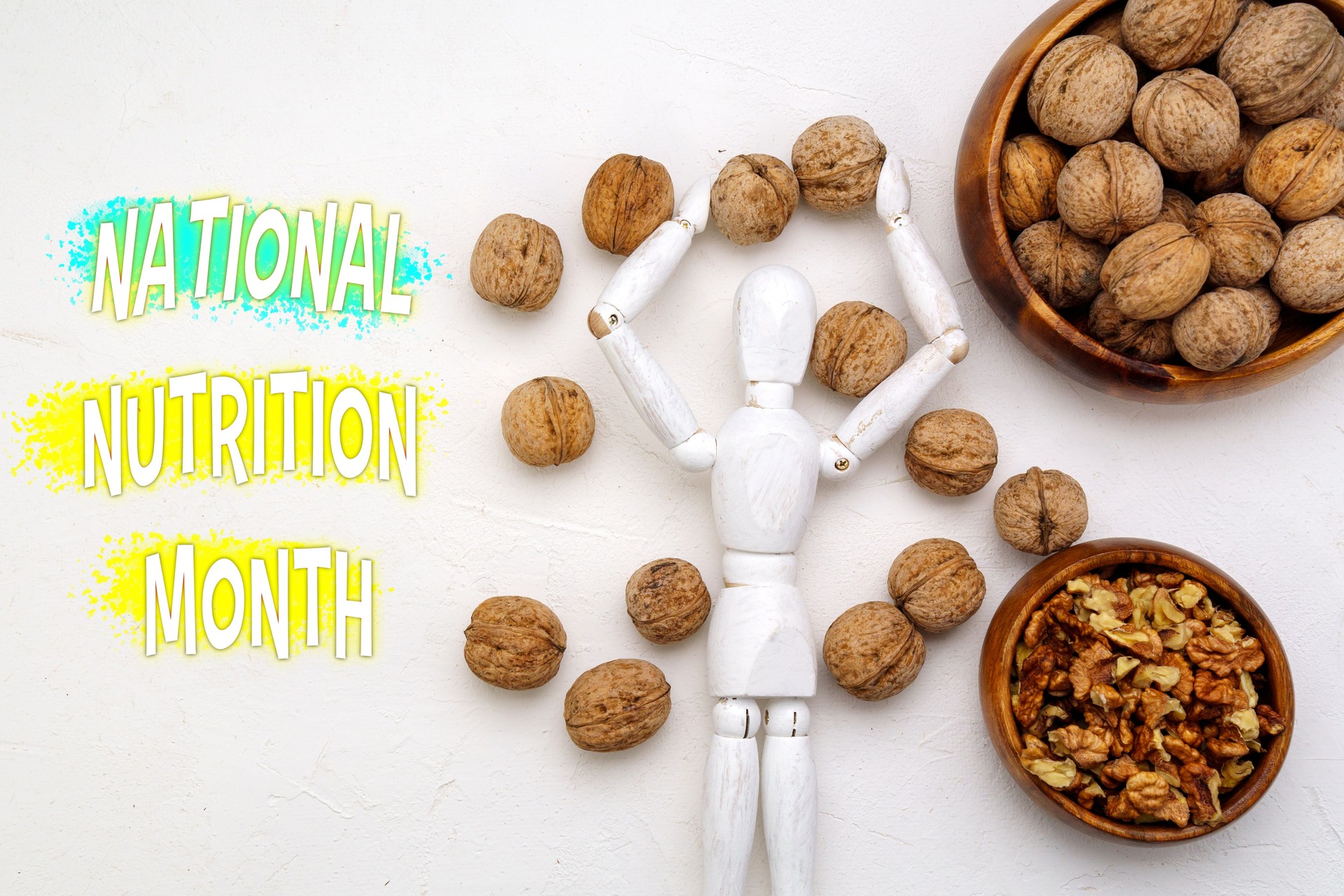 Una figura de madera que levanta triunfalmente los brazos entre nueces enteras y sin cáscara deletrea el significado del Mes Nacional de la Nutrición.